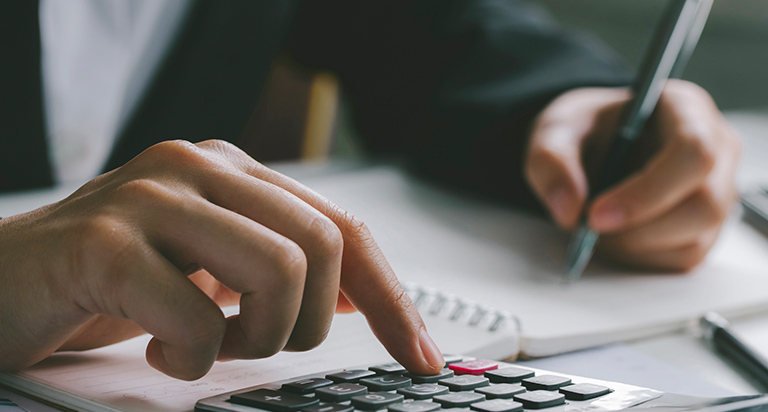 A person calculating their debt to income ratio with a pen and calculator