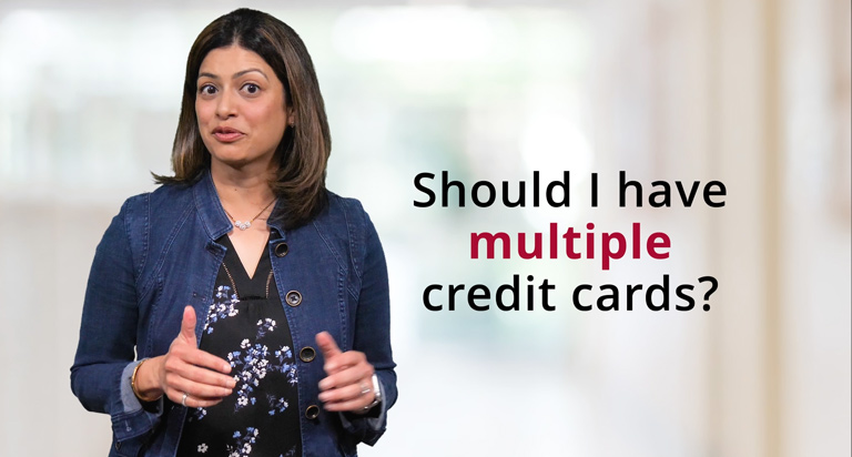 A dark haired woman, wearing a jean jacket and black blouse, stands next to the text, “Should I have multiple credit cards?”.