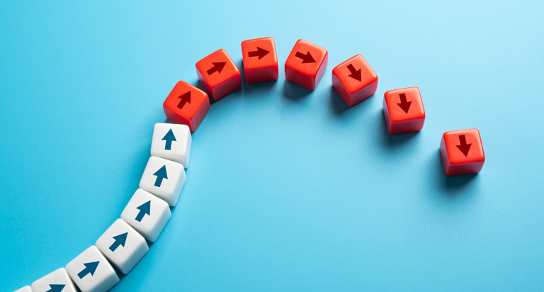 Dice-like cubes with arrows on the sides are lined up in a row that arcs up then down, turning white to red as they arc down.