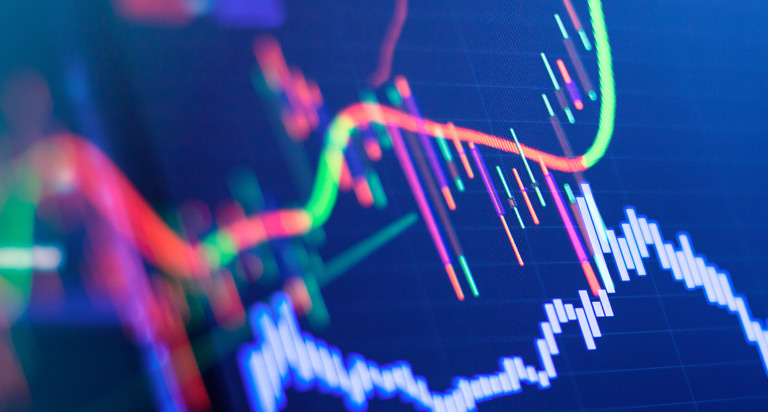 A side-angled view of a computer screen with red and green chart data showing stock market and trading information.