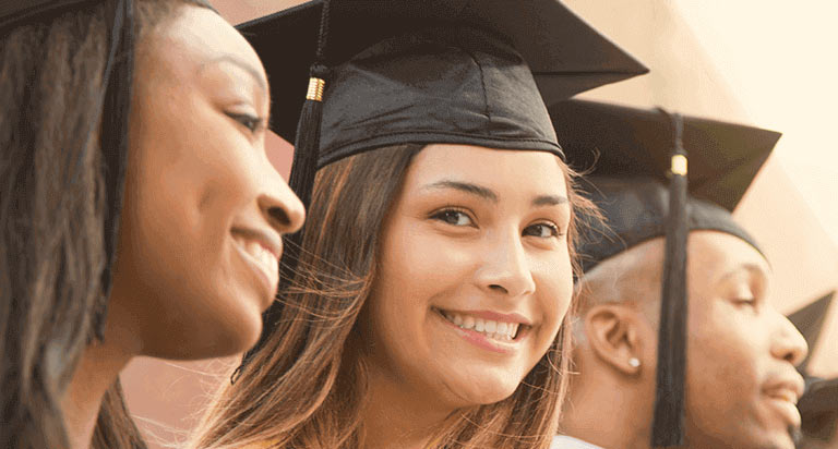 Three graduates standing next to each other and smiling