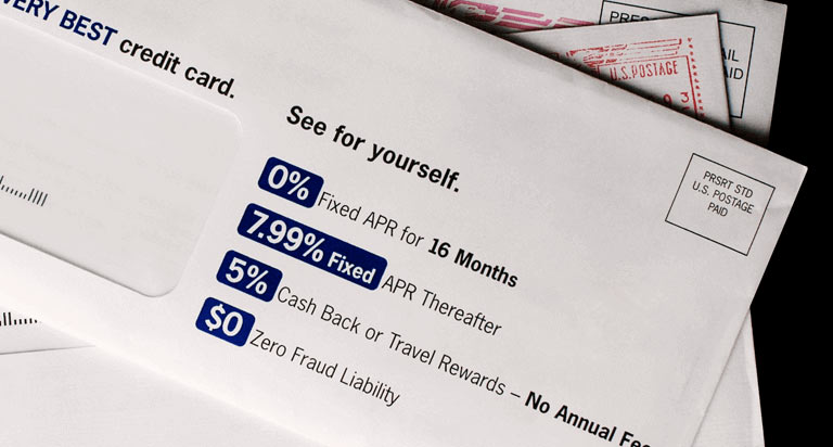 An white mailing envelope that lists the proposed benefits of a credit card offer inside the envelope on top of other pieces of mail