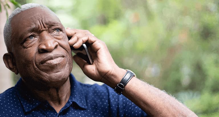 A concerned man looking up while he hold a cellphone to his left ear