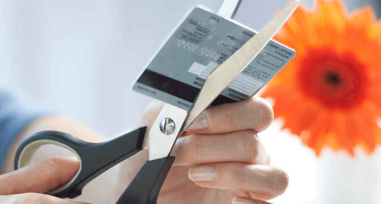 A person cutting their credit card using a pair of scissors
