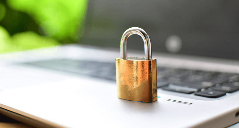 A golden lock sits on top of a laptop.