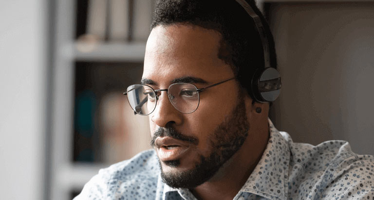 A man wearing glasses and a headset staring forward intently and down slightly