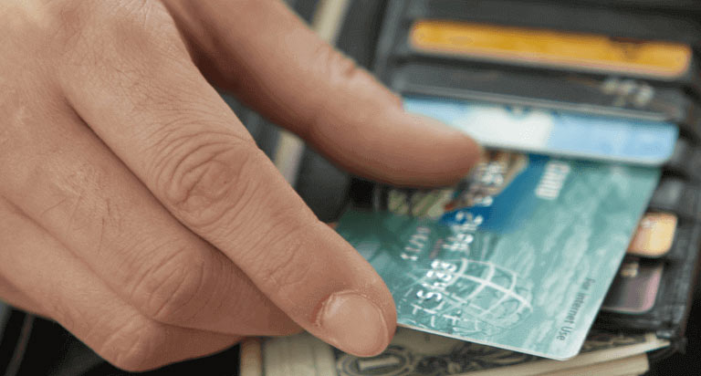 A hand placing a card back into a black leather wallet