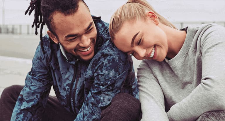 A woman leaning on a man while both of them smile