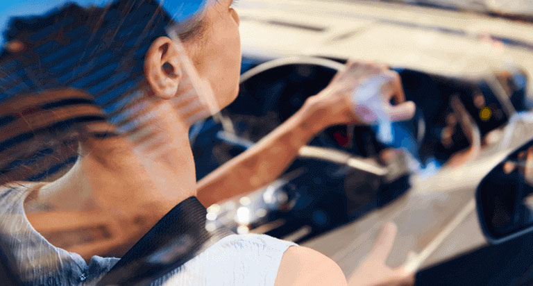 A woman driving a car, she is making a right turn.