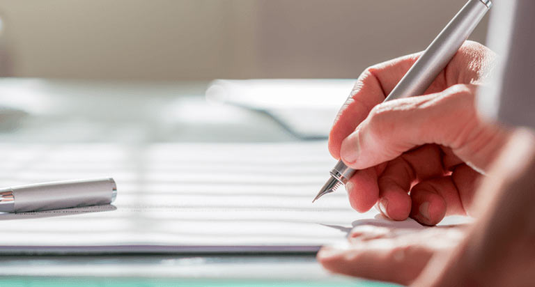 A person using a fountain pen to write something on a paper
