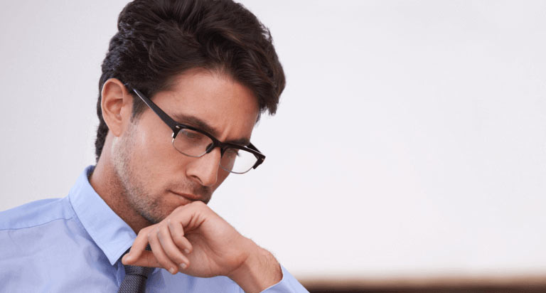 A man wearing glasses looking down and focusing