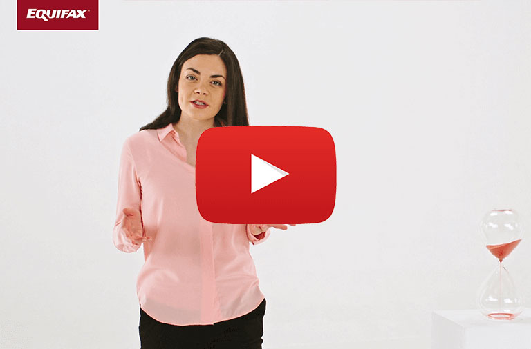 A woman stands next to an hourglass with red sand and a red box with EQUIFAX written in white letters in the upper left corner