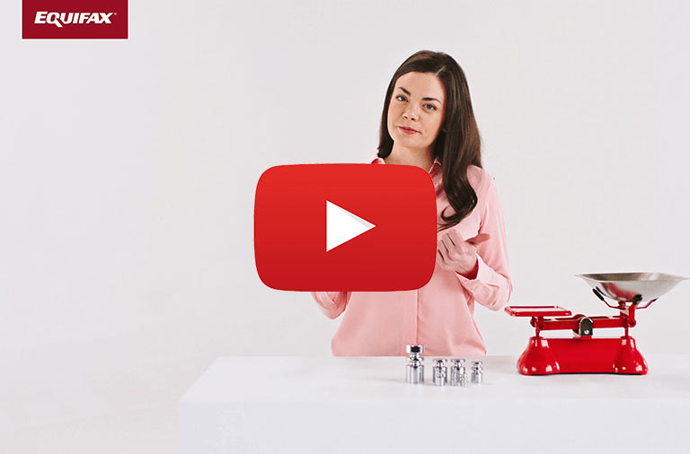 A woman stands next to a red scale with weights in front of her and a red box with EQUIFAX written in white letters in the upper left corner