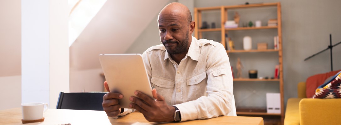 Person using a tablet at a table in a home setting to review personal information, such as a credit report.