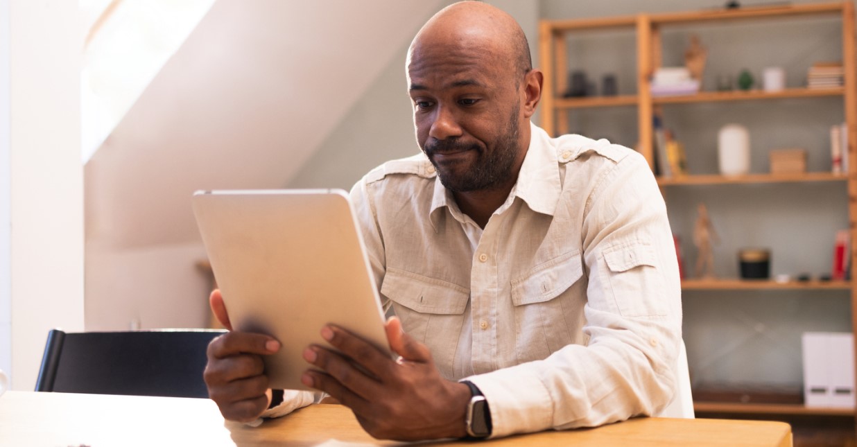 Person using a tablet at a table in a home setting to review personal information, such as a credit report.