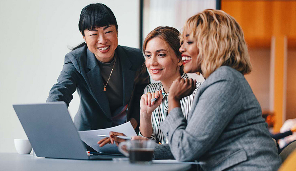 Três jovens analisam informação na área de trabalho do computador de um colega.