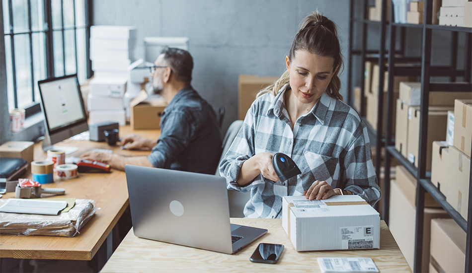 Mujer escanea códigos de cajas de paquetería en una oficina