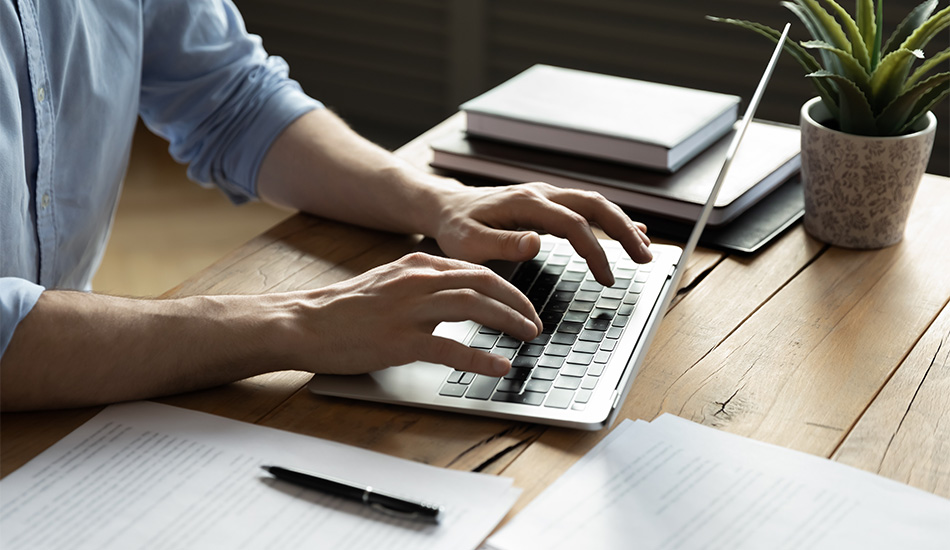 Joven escribe un documento importante en su computador portátil