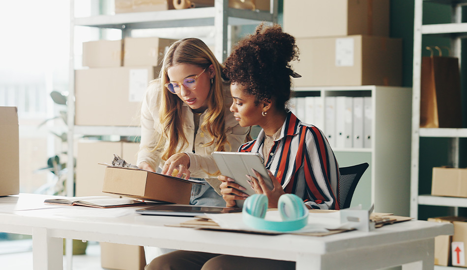 Mujeres revisan documentos de inventario y envíos sobre su tienda