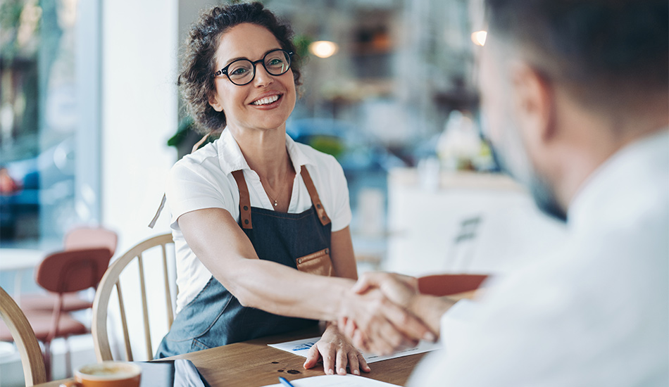 Mujer emprendedora sonríe mientras cierra un contrato de negocios en su cafetería
