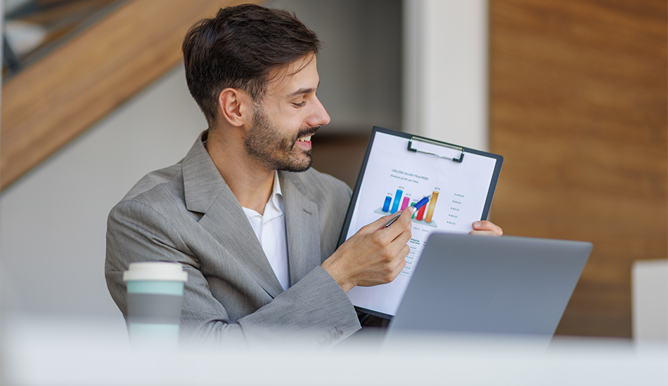 Hombre joven señala un gráfico sobre el papel que tiene en la mano
