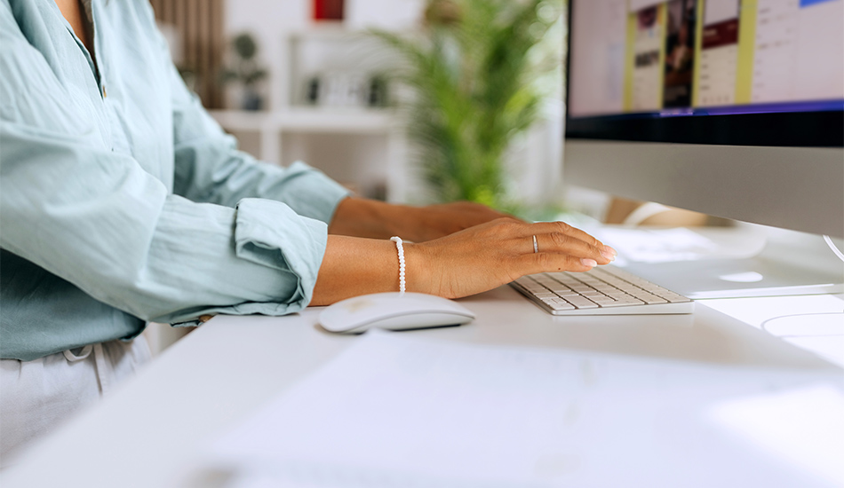 Manos de mujer teclean sobre una computadora de escritorio