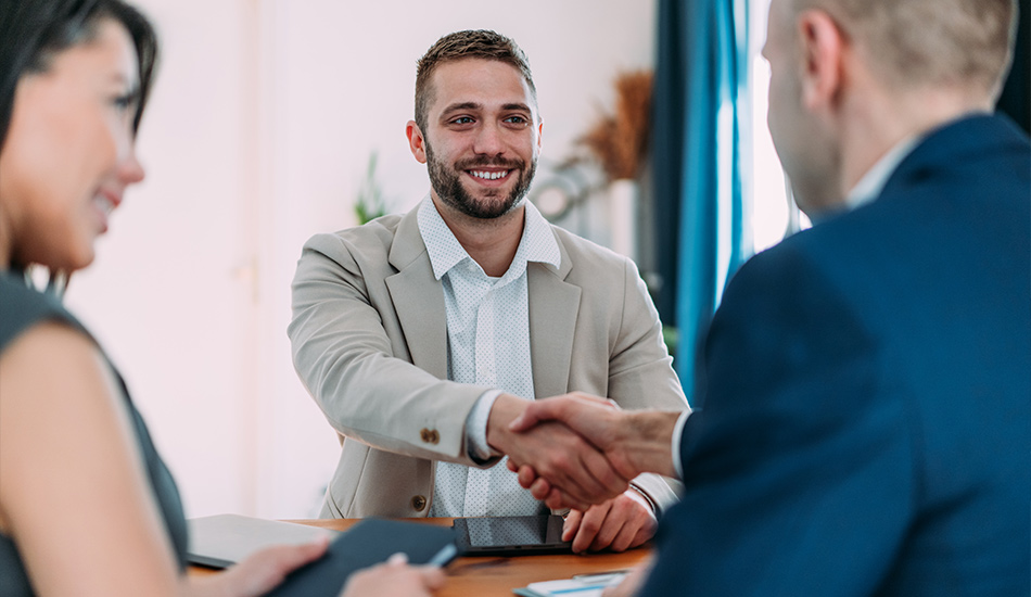 Hombres estrechan manos tras firmar un acuerdo beneficioso mutuo