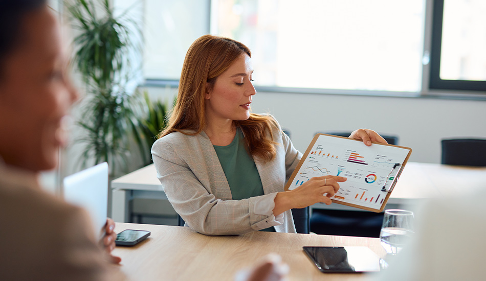 Mujer ejecutiva muestra múltiples gráficos en un documento a sus compañeros de oficina