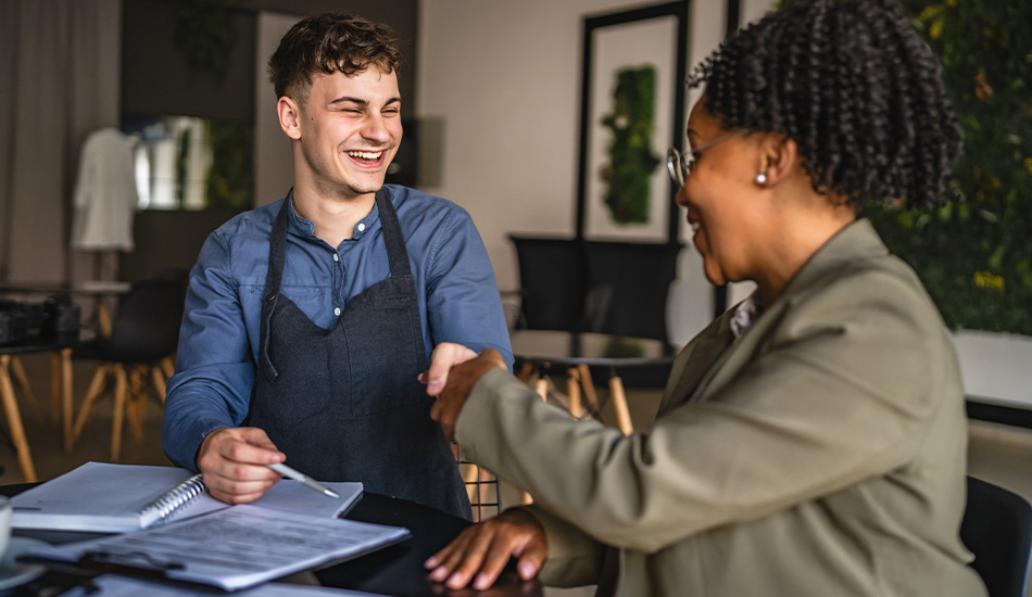 Joven en overol se muestra feliz tras firmar papeles en lo que parece un crédito para su restaurante