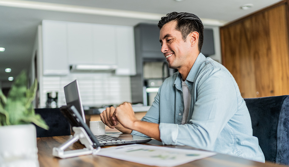 Hombre joven revisa datos y gráficos en su computador con una sonrisa en el rosto