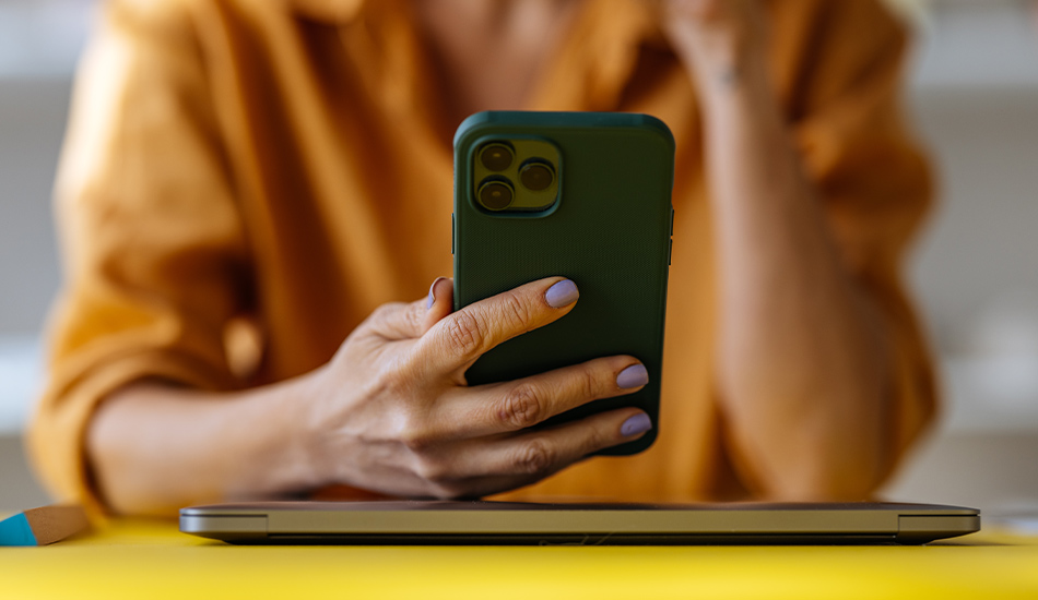 Manos delicadas de uñas pintadas sostiene un celular verticalmente hacia el rostro no visible de la mujer