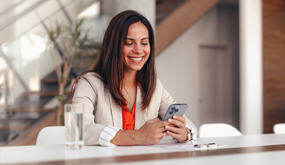 Mujer revisa las notificaciones en su teléfono celular desde el comedor de su casa