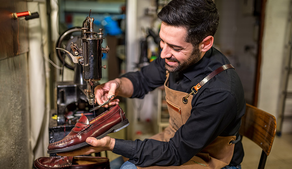 Young man repairs a leather shoe inside his workshop