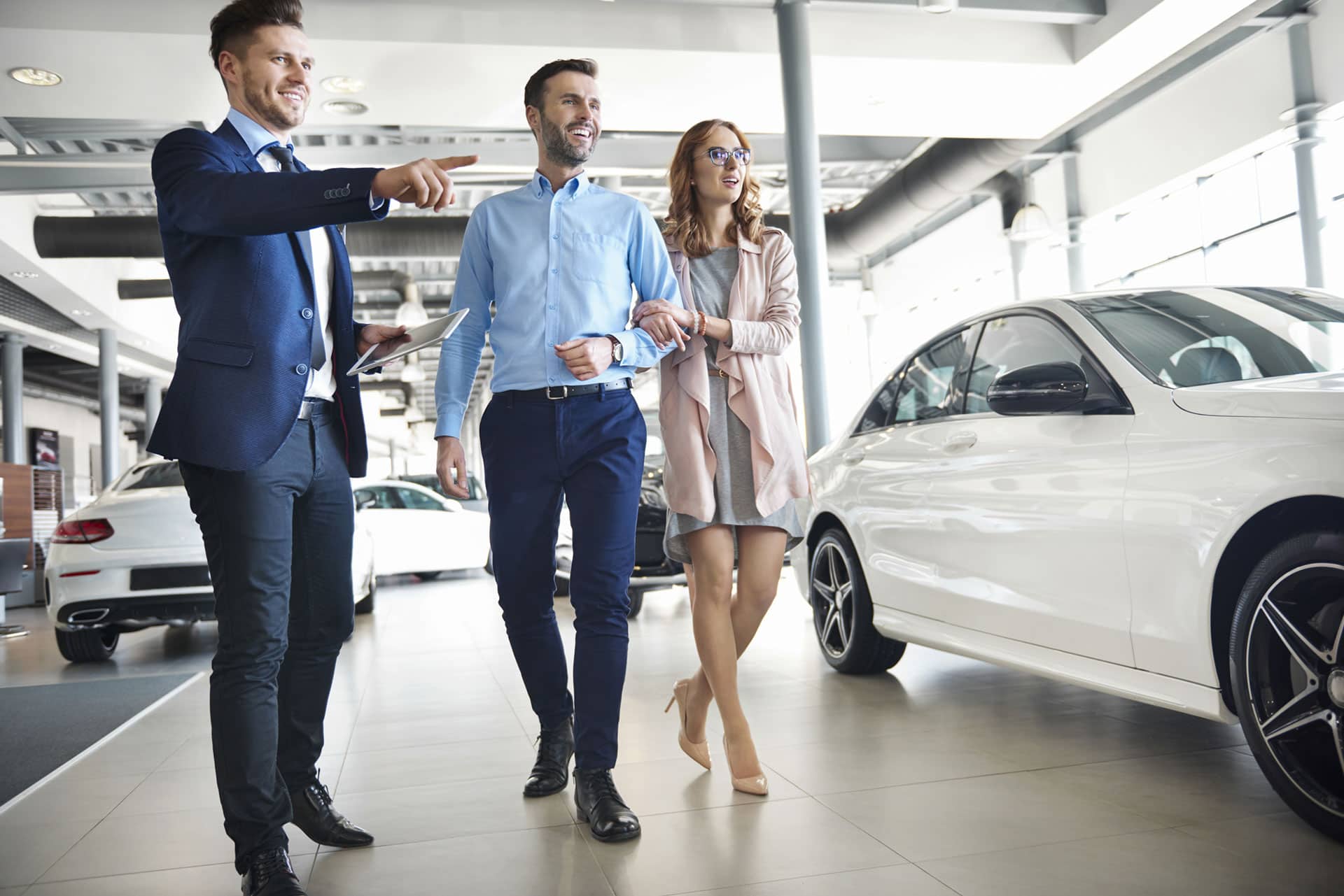 People looking at cars with a salesman showing options