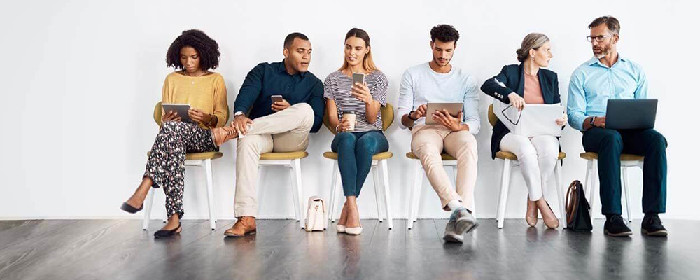 Group of professionals sitting in wooden chairs and working on their laptops and phones